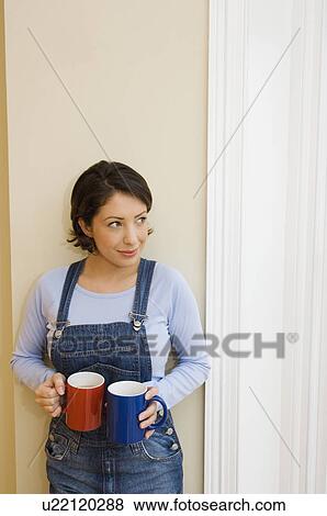 Stock Photo - Woman in overalls carrying coffee cups. Fotosearch