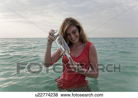 Woman in sea with message in a bottle View Large Photo Image Stock Photo - Woman in sea with message in a bottle. Fotosearch