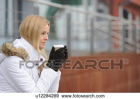 Stock Photo - Woman in winter clothes drinking coffee. Fotosearch