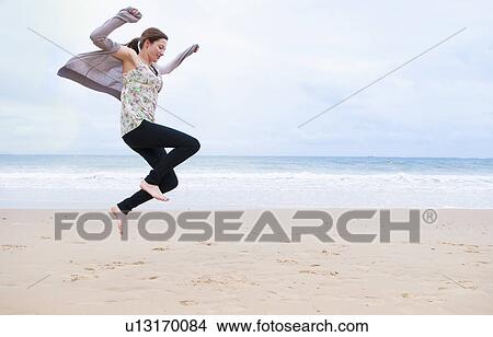 Picture - Woman jumping on beach. Fotosearch