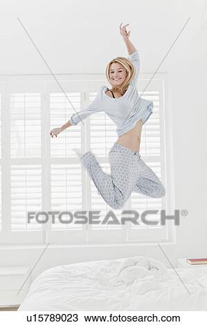 Woman jumping on bed View Large Photo Image Stock Image - Woman jumping on bed. Fotosearch