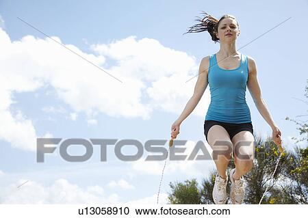 Stock Image - Woman jumping rope outdoors. Fotosearch