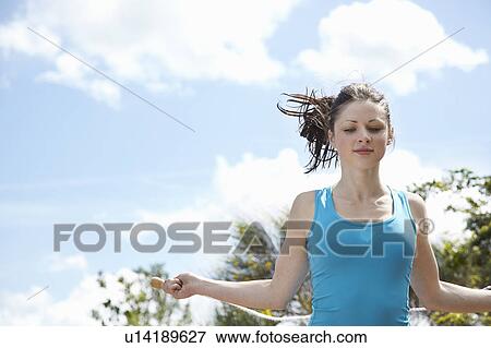 Stock Photo - Woman jumping rope outdoors. Fotosearch