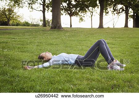 Woman laying in grass at park View Large Photo Image Stock Image - Woman laying in grass at park. Fotosearch
