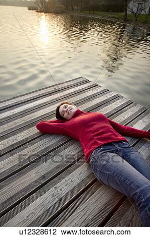 Woman laying on jetty over lake View Large Photo Image Stock Image - Woman laying on jetty over lake. Fotosearch