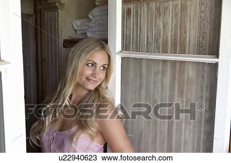 Stock Image - Woman leaning on bathroom door. Fotosearch