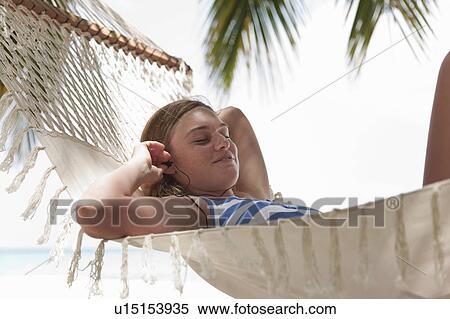 Woman listening to headphones in hammock View Large Photo Image Stock Photography - Woman listening to headphones in hammock. Fotosearch
