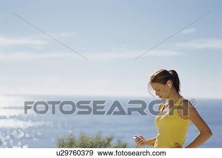 Woman listening to headphones outdoors View Large Photo Image Stock Photo - Woman listening to headphones outdoors. Fotosearch