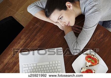 Stock Image - Woman lying on table with laptop. Fotosearch