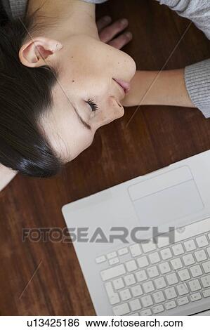 Stock Photograph - Woman lying on table with laptop. Fotosearch