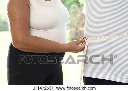 Stock Image - Woman measuring man’s waist. Fotosearch