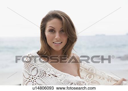 Stock Image - Woman on beach wrapped in blanket. Fotosearch