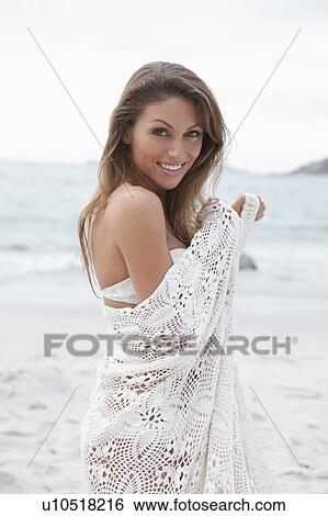 Stock Photograph - Woman on beach wrapped in blanket. Fotosearch