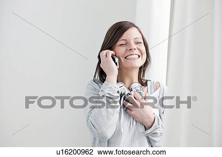 Stock Image - Woman on cell phone holding baby shoes. Fotosearch
