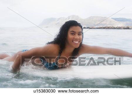 Stock Image - Woman on surfboard in water. Fotosearch