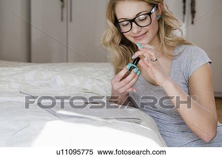 Woman painting her nails in bedroom View Large Photo Image Stock Photography - Woman painting her nails in bedroom. Fotosearch