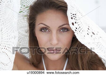 Picture - Woman peeking out from under blanket. Fotosearch