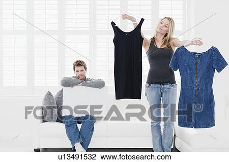 Stock Image - Woman picking out clothes in living room. Fotosearch