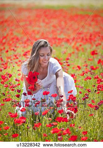 Stock Image - Woman picking poppies in field. Fotosearch
