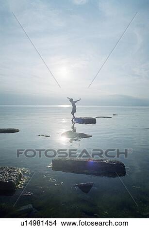 Woman playing on rocks in lake View Large Photo Image Picture - Woman playing on rocks in lake. Fotosearch