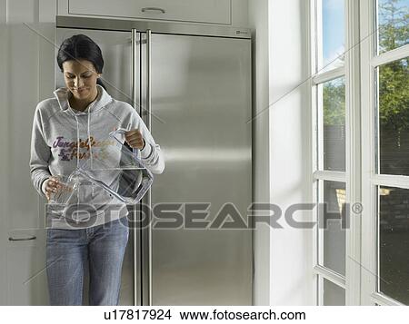 Woman pouring water into glass View Large Photo Image Picture - Woman pouring water into glass. Fotosearch