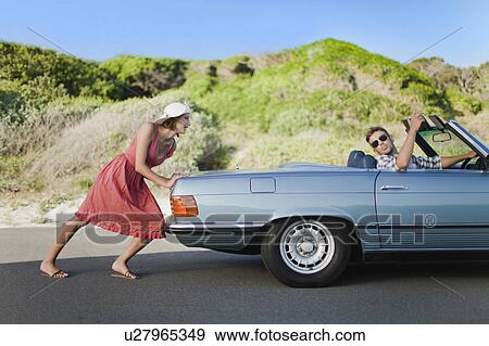 Woman pushing car as boyfriend steers View Large Photo Image Stock Photo - Woman pushing car as boyfriend steers. Fotosearch