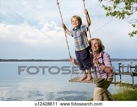 Woman pushing grandson on swing View Large Photo Image Stock Image - Woman pushing grandson on swing. Fotosearch