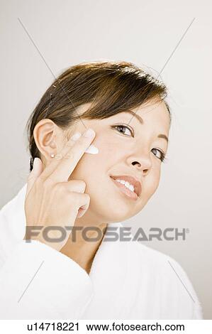 Woman putting moisturizer on her cheek View Large Photo Image Stock Image - Woman putting moisturizer on her cheek. Fotosearch