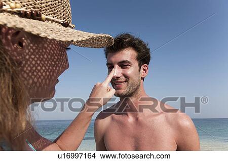 Picture - Woman putting sunscreen on boyfriend. Fotosearch