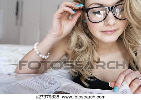 Stock Photo - Woman reading a magazine on bed. Fotosearch