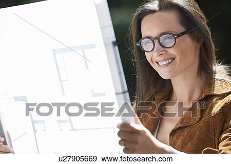 Woman reading blueprints outdoors View Large Photo Image Stock Photo - Woman reading blueprints outdoors. Fotosearch