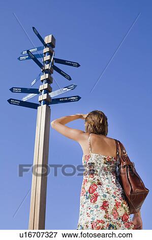 Stock Photo - Woman reading directions at crossroads. Fotosearch
