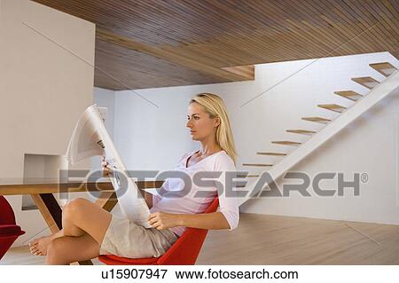 Stock Photo - Woman reading newspaper in dining room. Fotosearch