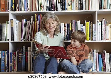Woman reading with grandson by bookshelf View Large Photo Image Stock Image - Woman reading with grandson by bookshelf. Fotosearch
