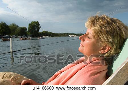 Woman relaxing in lawn chair by river View Large Photo Image Stock Image - Woman relaxing in lawn chair by river. Fotosearch