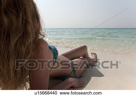 Stock Image - Woman relaxing in sand on beach. Fotosearch