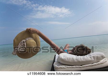 Stock Photo - Woman relaxing on daybed at beach. Fotosearch