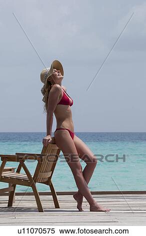 Stock Photography - Woman relaxing on deck overlooking sea. Fotosearch