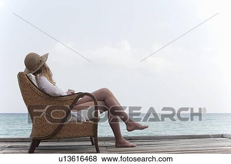 Stock Photo - Woman relaxing with coffee on deck. Fotosearch