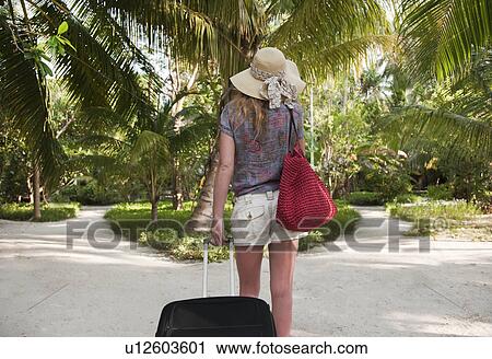 Woman rolling luggage in tropical resort View Large Photo Image Stock Image - Woman rolling luggage in tropical resort. Fotosearch
