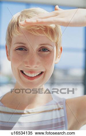 Stock Photography - Woman shielding eyes from sun. Fotosearch