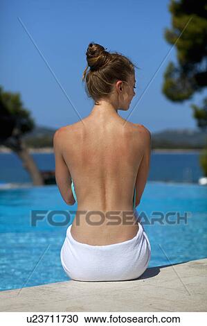 Stock Image - Woman sitting by swimming pool. Fotosearch