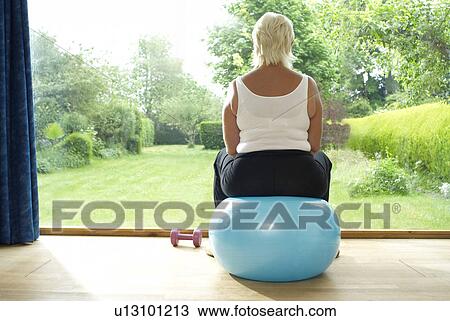 Woman sitting on exercise ball indoors View Large Photo Image Stock Image - Woman sitting on exercise ball indoors. Fotosearch