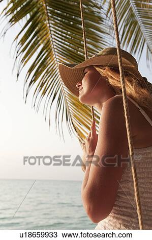 Stock Image - Woman sitting on swing at beach. Fotosearch