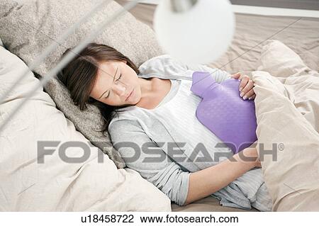 Stock Image - Woman sleeping with hot water bottle. Fotosearch