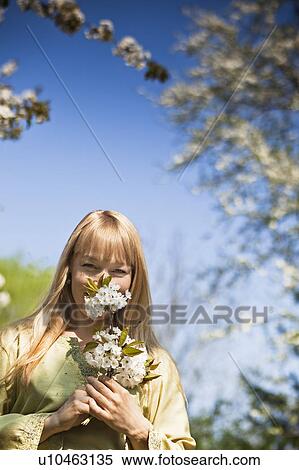 Stock Photography - Woman smelling flowers outdoors. Fotosearch