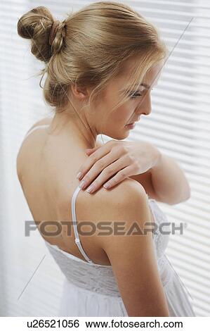 Stock Photograph - Woman standing at window blinds. Fotosearch