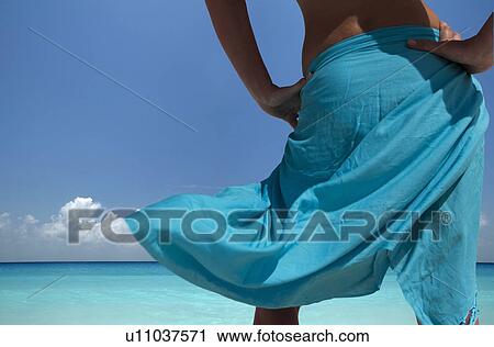 Stock Image - Woman standing on tropical beach. Fotosearch