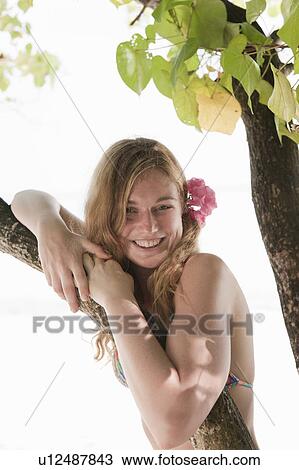 Stock Image - Woman standing under tree on beach. Fotosearch
