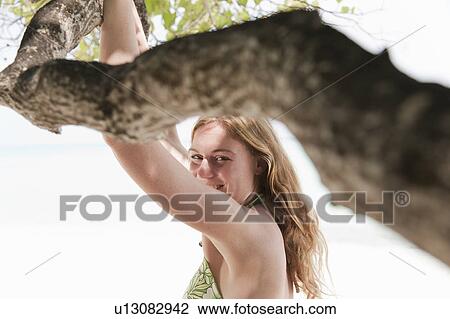 Woman standing under tree on beach View Large Photo Image Stock Image - Woman standing under tree on beach. Fotosearch